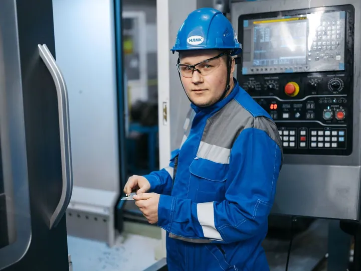 Engineer in safety gear operating a CNC machine in a factory