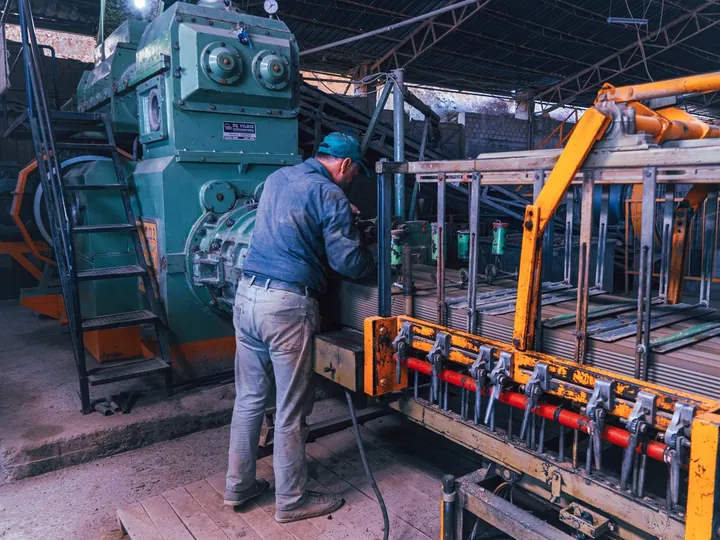 Factory worker operating industrial machinery in a production hall